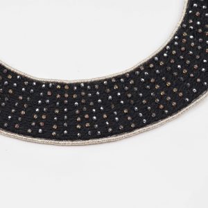 Close-up of a black collar necklace showing small faceted glass beads hand-set using a traditional pearl setting technique on a textile base.