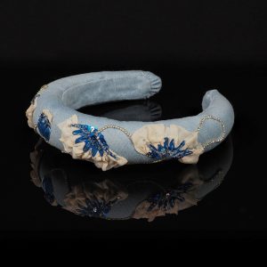 Side view of a one-of-a-kind light blue denim headband featuring hand-embroidered poppy motifs in blue sequins, cream chiffon, beads, and rhinestone chain