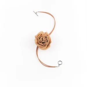 Flat lay of handcrafted gold silk rose choker with suede lace and toggle clasp displayed on white background