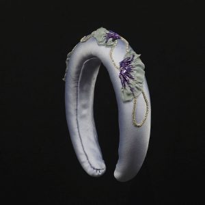 One-of-a-kind lavender satin headband featuring hand-embroidered purple poppy motifs with grey chiffon petals, sequins, and rhinestone chain, displayed upright