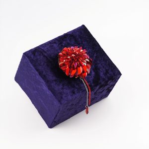 Handmade red dahlia brooch displayed on a dark velvet box, highlighting the intricate beading and limited edition design