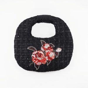 Hand-embroidered black tweed bag with red and silver camellia design, rounded shape, and maroon lining, designed by Ksenia Semirova